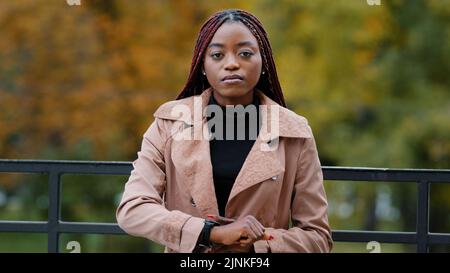 Verärgert frustriert afroamerikanische Frau zeigt auf der Uhr, Minuten zählen, hetzen. Portrait von schönen afro Mädchen stehen im Herbst Park allein Stockfoto