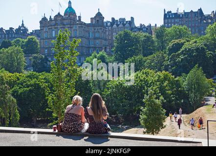 Edinburgh City Centre, Schottland, Großbritannien. 12.. August 2022. Edinburgh ist am 8.. Tag des Edinburgh Festival Fringe an verschiedenen Orten in der Hauptstadt für das Ende der ersten vollen Woche beschäftigt. Temperatur 21 Grad Celsius für alle, die draußen sind. Im Bild: Menschen, die das heiße Wetter genießen, sich entspannen und in den Princes Street Gardens East spazieren gehen Credit: Arch White/alamy Live News. Stockfoto