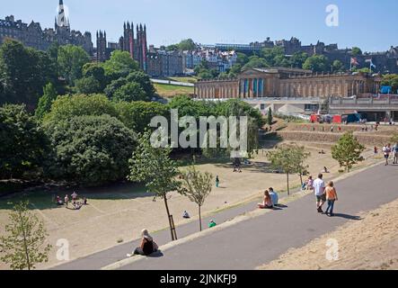 Edinburgh City Centre, Schottland, Großbritannien. 12.. August 2022. Edinburgh ist am 8.. Tag des Edinburgh Festival Fringe an verschiedenen Orten in der Hauptstadt für das Ende der ersten vollen Woche beschäftigt. Temperatur 21 Grad Celsius für die draußen und draußen, ausgetrockntes Gras aufgrund des Fehlens von Niederschlägen. Im Bild: Menschen, die das heiße Wetter genießen, sich entspannen und in den Princes Street Gardens East spazieren gehen Credit: Arch White/alamy Live News. Stockfoto