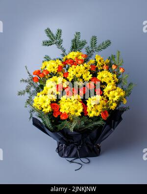 Originelles Bouquet aus kleinen rosa Rosen, gelben Chrysanthemen und Fichtenzweigen. Stockfoto