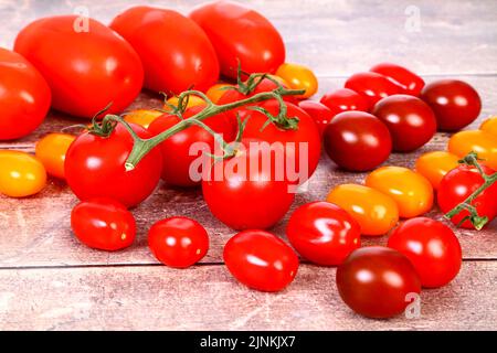 Nahaufnahme einer Mischung reifer Tomaten auf einer Holzplatte Stockfoto