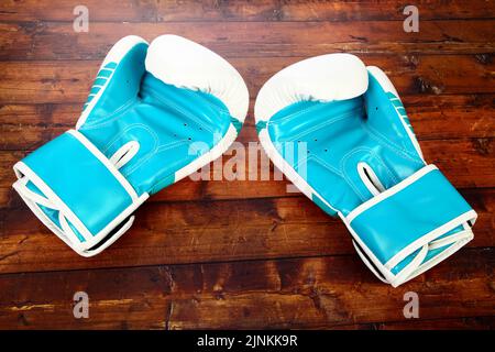 Zwei blaue Boxhandschuh isoliert auf einem hölzernen Hintergrund Stockfoto