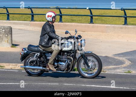 Triumph Bonneville T100 '911 CARRERA, MILANO' - Deus Milano Motorradfahrer in der Werkstatt; Fahrt auf der Küstenstraße in Southport, Großbritannien Stockfoto