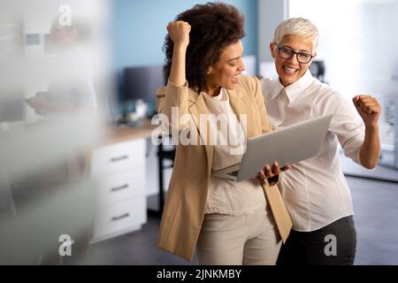 Glückliche, multiethnische, lächelnde Geschäftsfrauen, die im Büro zusammenarbeiten Stockfoto