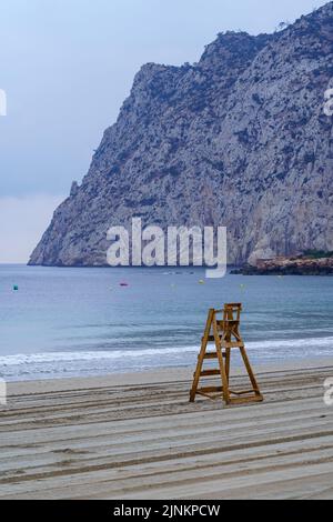 Rettungsschwimmer Holzstuhl neben großen Klippen. Calpe Alicante. Stockfoto
