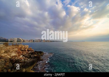 Blick auf die Sommerstadt am Meer bei einem goldenen Sonnenuntergang mit atemberaubenden Wolken. Stockfoto