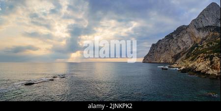 Panorama-Seesicht mit großem Berg am Meer und goldenem Sonnenuntergang. Stockfoto