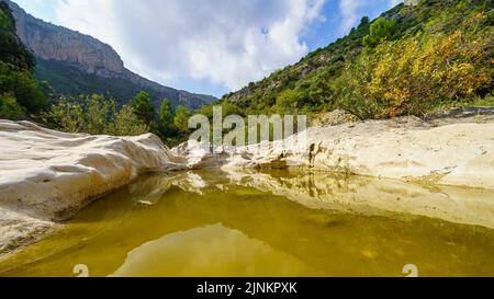 Strom zwischen erodierten Felsen im Tal zwischen Bergen. Stockfoto