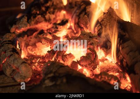 Feuer und Glut aus Eichenholz in einem gemütlichen Kamin im Winter. Stockfoto