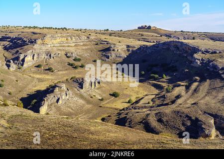 Eine unreine Berglandschaft mit Schluchten und einem kleinen Haus auf dem Gipfel des Berges. Stockfoto