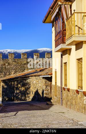 Malerische Häuser neben der mittelalterlichen Mauer und schneebedeckte Berge im Hintergrund. Buitrago de Lozoya Madrid. Stockfoto