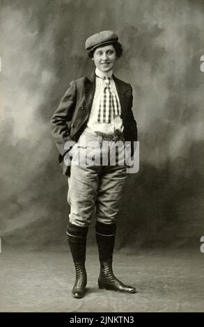 Formelles Vintage-Studioporträt in Schwarz und Weiß mit androgyner Person, die ein Herrenfahrrad oder einen Golfanzug mit Mütze und Schnürstiefeln um 1895 trägt Stockfoto