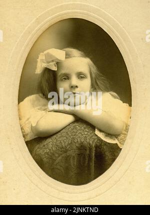Fotografisches Porträt eines jungen Mädchens mit Bogen im Haar, das die edwardianische Kleidung trug, Kabinettkarte um 1911 Stockfoto