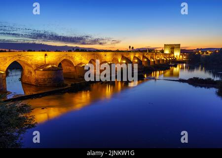 Römische Brücke mit Bögen über dem Guadalquivir-Fluss bei Sonnenuntergang an einem ruhigen Tag. Cordoba Spanien. Stockfoto