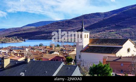 Alte Kirche mit Glockenturm in einem alten Dorf im grünen Tal der hohen Berge. Lozoya Spanien. Stockfoto