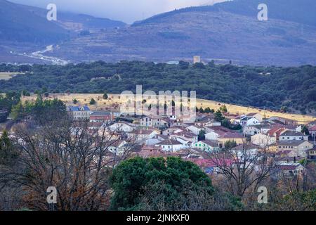 Bergdorf am Hang mit grüner Vegetation und Nebel im Hintergrund. Somosierra, Segovia. Stockfoto