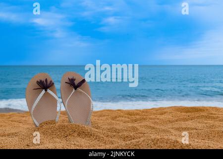 Strandschuhe auf dem Sand mit dem Meer im Hintergrund Stockfoto