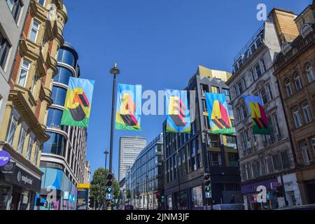 London, Großbritannien. 12.. August 2022. Entlang der Oxford Street wurde eine neue Kunstinstallation mit Fahnen mit der Aufschrift „Time for Clean Power“ aus recyceltem Ozeanplastik installiert, um den Wechsel zu erneuerbaren Energien zu fördern. Die Installation wurde vom britischen Künstler Morag Myerscough entworfen, der Teil einer von #TOGETHERBAND finanzierten Kampagne ist. Kredit: Vuk Valcic/Alamy Live Nachrichten Stockfoto