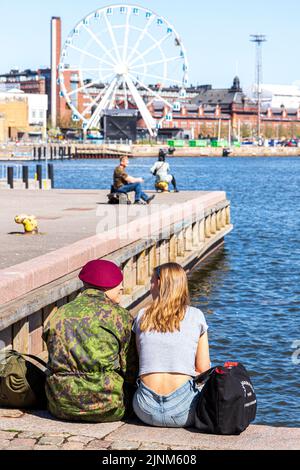 Ein junges Paar, das am Hafen in Helsinki, Finnland, sitzt Stockfoto