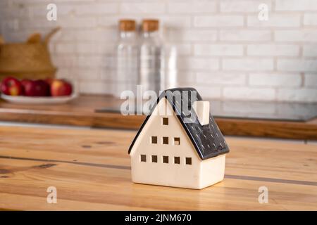 Ein Modell eines Hauses auf dem Hintergrund von Küchenmöbeln. Das Konzept des Kaufs eines Hauses, Hypothek Immobilien, Wohnküche Interieur