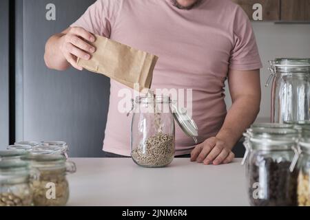 Nicht erkennbarer lateinischer Mann, der ein Glas mit geschälten Sonnenblumenkernen füllte. Stockfoto