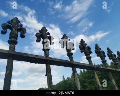 Schwarze Geländer mit Fleur de lys-Gipfeln gegen den blau bewölkten Himmel Stockfoto