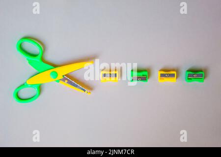 Zurück zum Schulkonzept mit Schulbedarf, Scheren und Bleistiftspitzer auf grauem Hintergrund. Draufsicht mit Kopierbereich. Flach liegend. Stockfoto