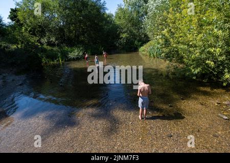 Chorleywood, Großbritannien. 12. August 2022. Wetter in Großbritannien – Jungen spielen im kristallklaren Wasser des River Chess in Chorleywood, Hertfordshire, was Beweise dafür zeigt, dass es viel niedriger als üblich ist. Als Kreidestrom hat es eine besondere Bedeutung für die Tierwelt und die natürliche Umwelt. Heute wurde Hertfordshire zu einem von 14 Gebieten, die von der Umweltbehörde als ‘Dürre’ eingestuft wurden. Kredit: Stephen Chung / Alamy Live Nachrichten Stockfoto