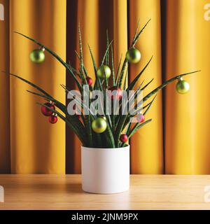 Quadratische Weihnachtskomposition. Grüne Hauspflanze mit Weihnachtskugeln vor gelben Vorhängen, Vorderansicht. Stockfoto