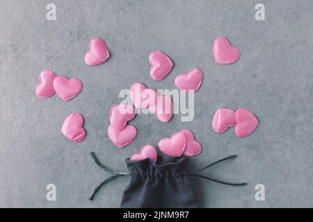 Romantisches Flatlay aus seidenrosa Herzen und Seidenbeutel auf grauem Steingrund. Liebe, Valentinstag, dekoratives Konzept. Stockfoto