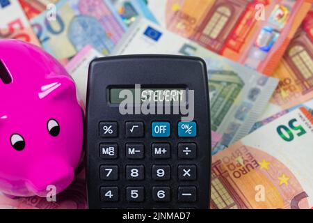 Rechner mit dem Wort Steuern, Übersetzung Steuern auf dem Display vor den Banknoten Stockfoto