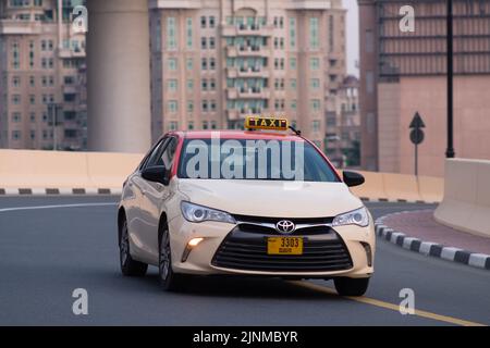 Nahaufnahme von Dubai Taxi, das eine Kurve auf der Straße in der Stadt Dubai, Vereinigte Arabische Emirate, passiert. Aufgenommen am Tag. Gebäude im Hintergrund. Stockfoto