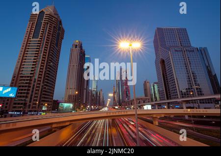 Ein breites Bild des Verkehrs und der Gebäude entlang der Sheikh Zayed Road, der längsten Autobahn in Dubai und den Vereinigten Arabischen Emiraten. Stadtbild bei Nacht. Stockfoto