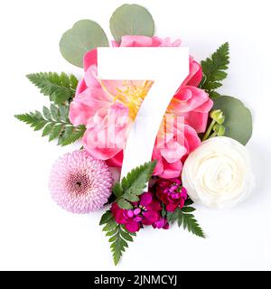 Kreatives Layout mit bunten Blumen, Blättern und Nummer sieben isoliert auf weißem Hintergrund. Jubiläumskonzept. Flach liegend. Stockfoto