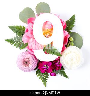 Kreatives Layout mit bunten Blumen, Blättern und Nummer neun isoliert auf weißem Hintergrund. Jubiläumskonzept. Flach liegend. Stockfoto