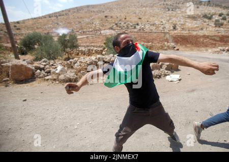 Nablus, Westjordanland, Palästina. 2. August 2022. Ein palästinensischer Protestler schleudert Steine auf die israelischen Soldaten während der Demonstration gegen israelische Siedlungen im Dorf Beit Dajan in der Nähe der Stadt Nablus im Westjordanland. (Bild: © Nasser Ishtayeh/SOPA Images via ZUMA Press Wire) Stockfoto