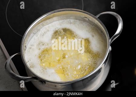 Kartoffelkeile, die in einem Topf auf einem Induktionsherd gekocht werden. Kochen zu Hause Stockfoto