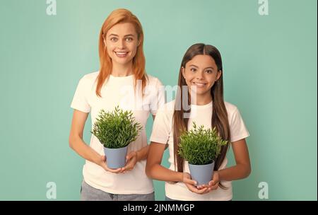 Glückliche Frau Mutter und adoptierte Tochter Kind lächeln mit Topfpflanzen blauen Hintergrund, Pflege Stockfoto