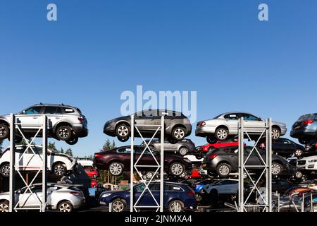 Profilansicht von Altmotorwagen, die an Verkehrsunfällen beteiligt sind, die auf Regalen in einem Schrott-Händler-Junk-Yard mit Kopierfläche gestapelt sind Stockfoto