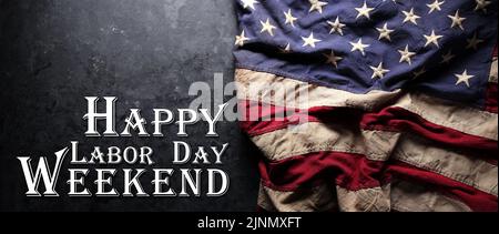 US-amerikanische Flagge auf abgenutztem schwarzem Hintergrund. Zur Feier des USA Labor Day. Mit Happy Labor Day Weekend Text. Stockfoto