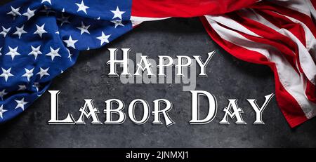 US-amerikanische Flagge auf abgenutztem schwarzem Hintergrund. Zur Feier des USA Labor Day. Mit Happy Labor Day Text. Stockfoto