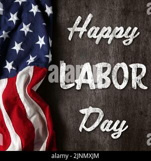 US-amerikanische Flagge auf abgenutztem schwarzem Hintergrund. Zur Feier des USA Labor Day. Mit Happy Labor Day Text. Stockfoto