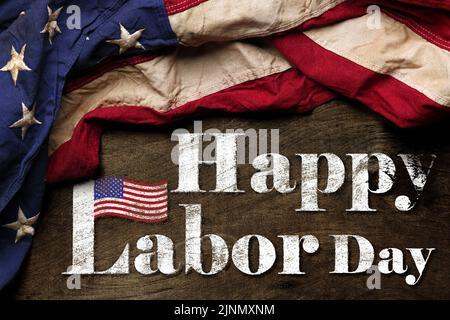 US-amerikanische Flagge auf abgenutztem schwarzem Hintergrund. Zur Feier des USA Labor Day. Mit Happy Labor Day Text. Stockfoto