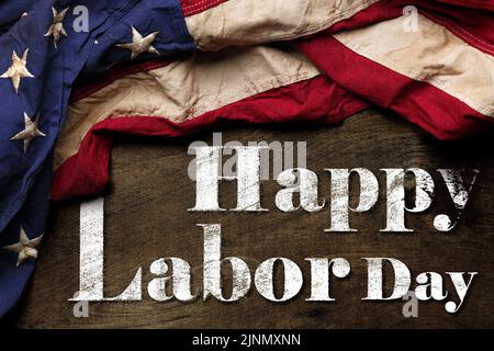 US-amerikanische Flagge auf abgenutztem schwarzem Hintergrund. Zur Feier des USA Labor Day. Mit Happy Labor Day Text. Stockfoto