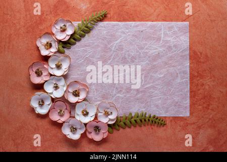 Faserpapier und Papierblumen auf strukturiertem orangefarbenem Hintergrund Stockfoto