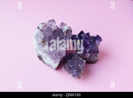Drei schöne lila drusen mit Amethyst-Kristallen auf einem rosa Hintergrund. Magische Halbedelsteine. Stockfoto