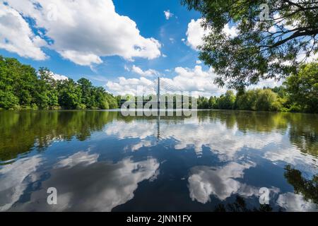 Glänzende, gewellte Wasseroberfläche mit Spiegelung des Himmels. Idyllische Sommerlandschaft mit Straßenseilbrücke über den Jordan-Teich in der südböhmischen Stadt Tabor. Stockfoto