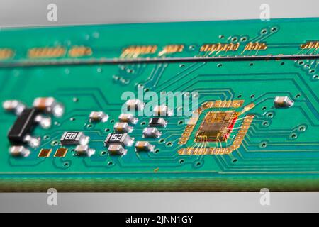 Golddrähte mit Chip-Bonding und grünen PCB-Details vom Flachbettscanner. Integrierte Leiterplatte, die mit einer Line-Scan-Kamera mit einer elektronischen Leiterplatte verdrahtet ist. Stockfoto