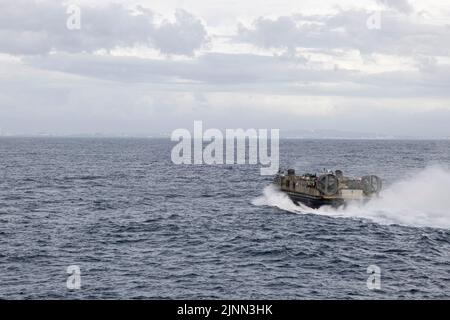 Ein Landungsschiff der US Navy, Luftkissen mit Naval Beach Unit 7, fliegt während des Brunnendecks an Bord der USS New Orleans (LPD 18) in der philippinischen See, 1. August 2022, an Land. Landungsboote, Luftkissen werden verwendet, um Fahrzeuge und Personal von Schiff zu Land zu transportieren. Die 31. MEU ist an Bord der Schiffe der Expeditionary Strike Group von Tripolis im Einsatzgebiet der 7. Flotten tätig, um die Interoperabilität mit Verbündeten und Partnern zu verbessern und als einsatzbereite Einsatztruppe für Frieden und Stabilität in der Indo-Pazifik-Region zu dienen. (USA Marine Corps Foto von Sgt. Danny Gonzalez) Stockfoto