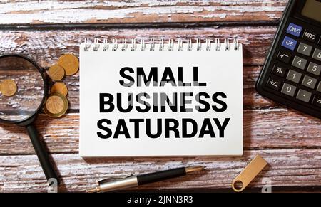 Text Small Business Saturday in Notebook auf weißem Tisch mit Office-Tools. Stockfoto